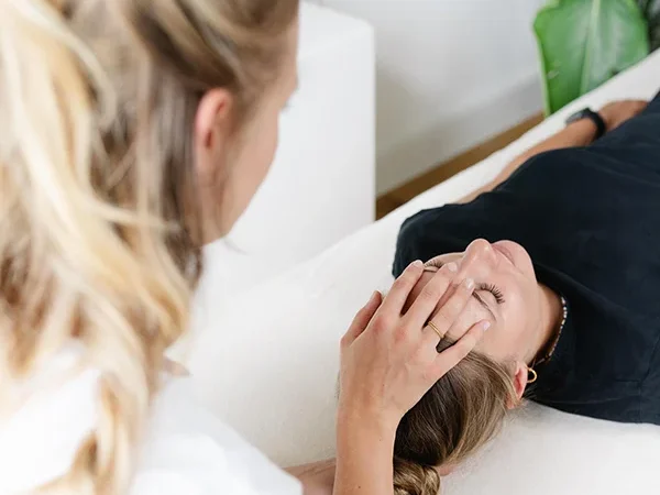 Nahaufnahme der Osteopathin, die den Kopf einer Patientin in Rückenlage behandelt.
